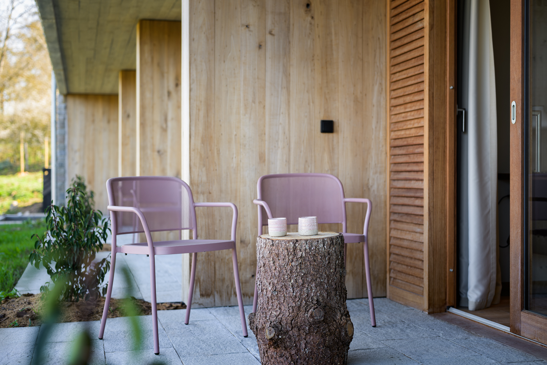 Terrasse privative d'une chambre avec deux chaises et une souche en bois